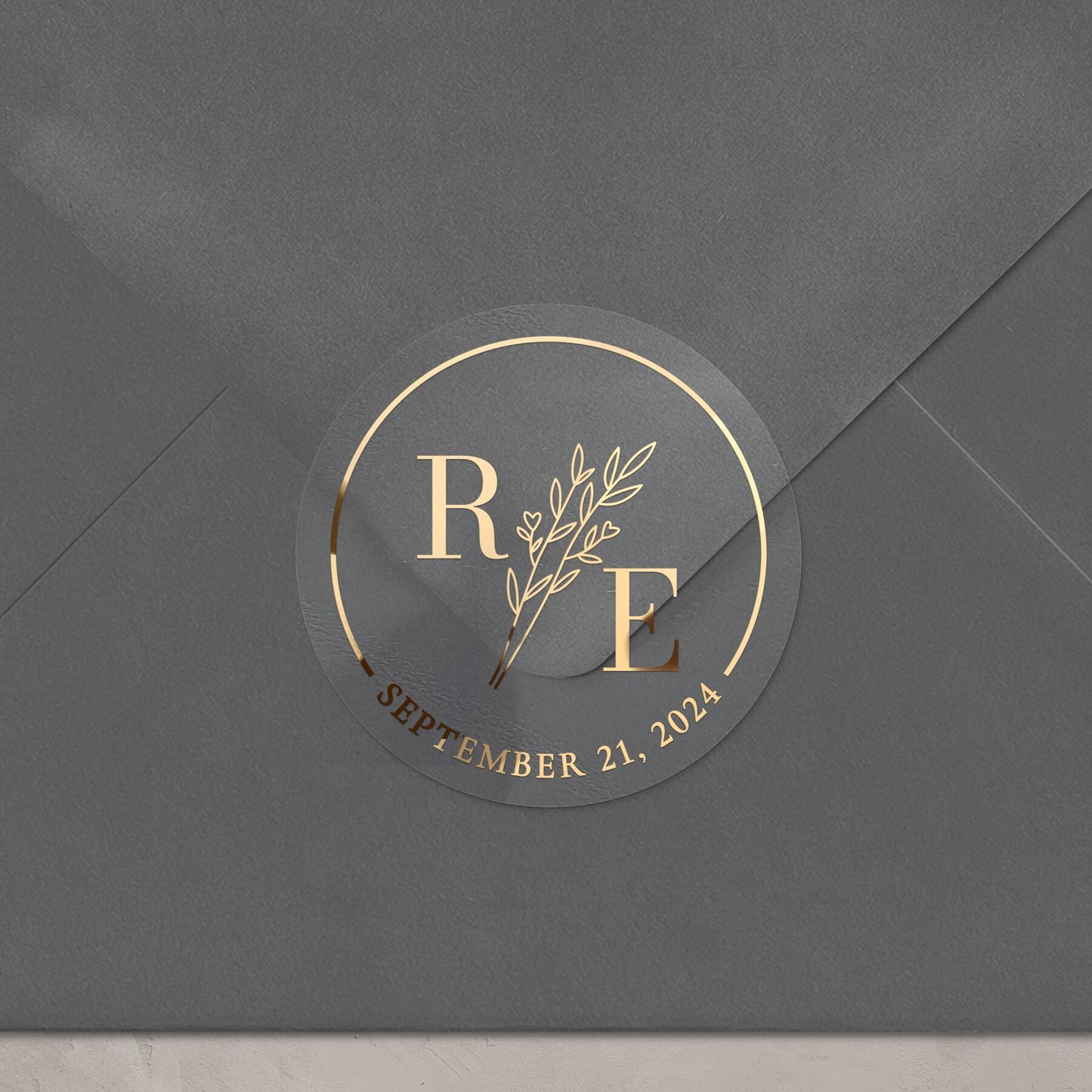 Transparent wedding sticker with golden initials and date, featuring an elegant botanical design