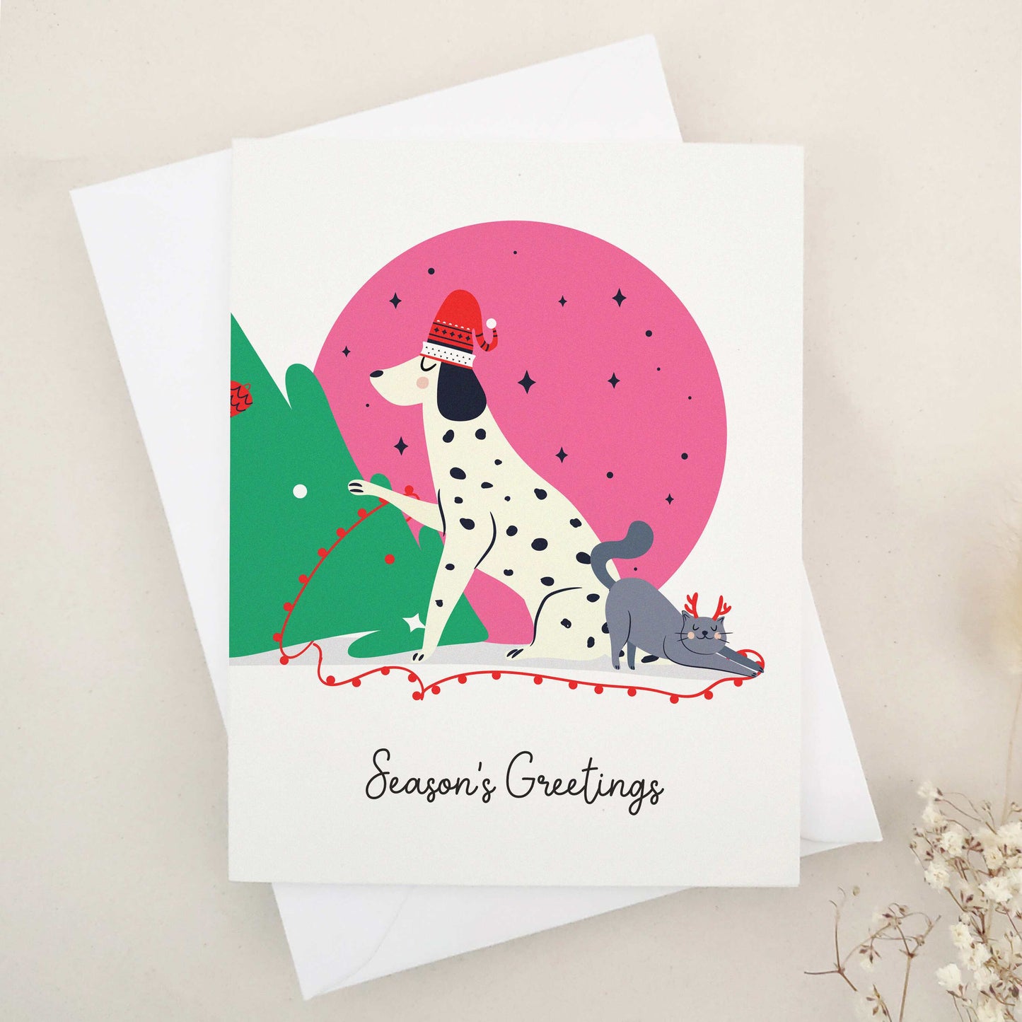 Unleash the holiday spirit with our adorable 'Season's Greetings' card, featuring a festive spotted dog and a cheerful companion decorating a Christmas tree under a starry night sky, perfect for dog lovers and fans of playful designs.