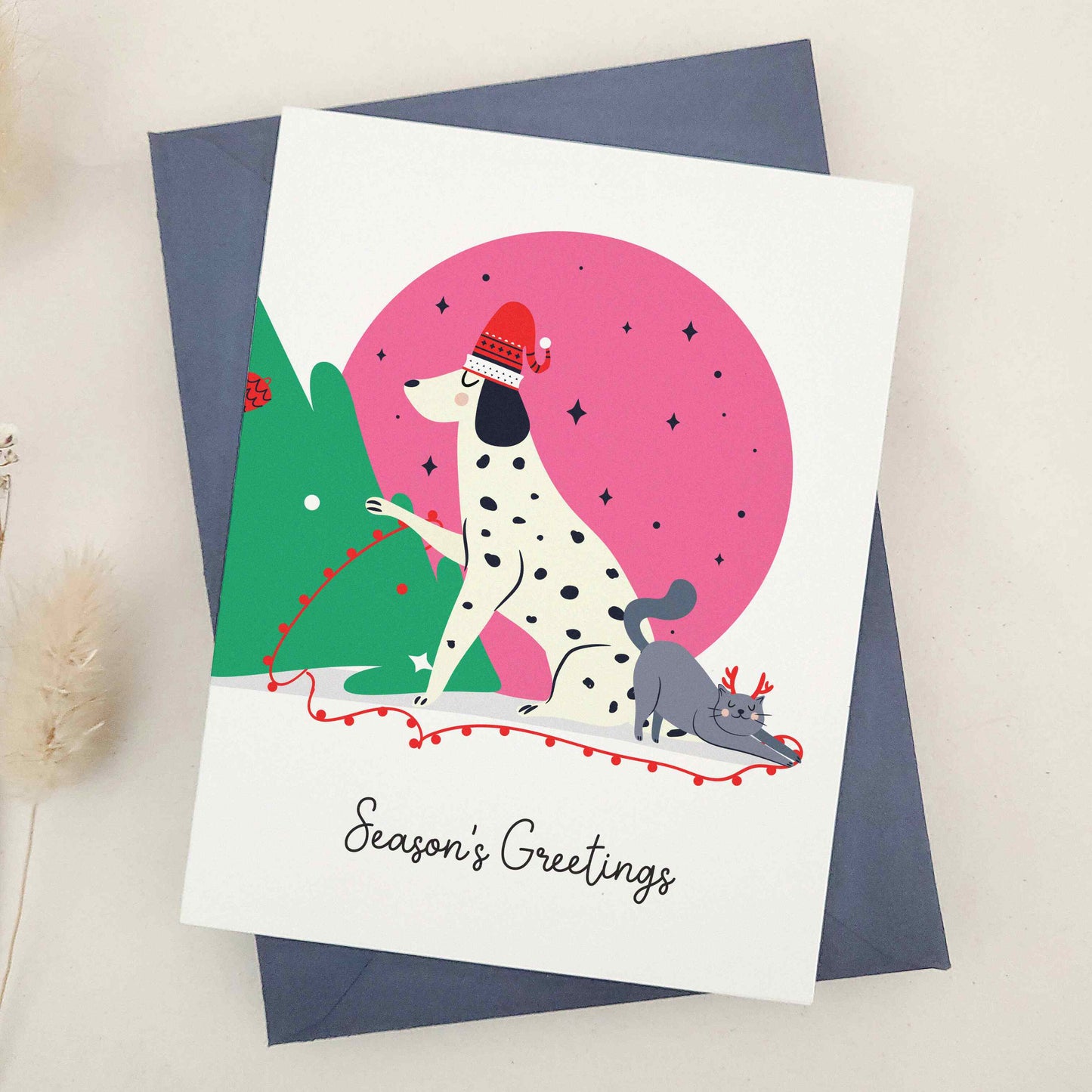 Unleash the holiday spirit with our adorable 'Season's Greetings' card, featuring a festive spotted dog and a cheerful companion decorating a Christmas tree under a starry night sky, perfect for dog lovers and fans of playful designs.