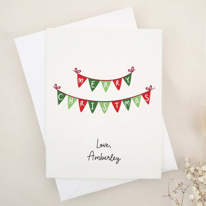 Embrace the festive season with our classic 'Merry Christmas' card: a beautifully simple yet elegant choice featuring traditional Christmas bunting in warm holiday colors, delicately spelling out heartfelt holiday greetings.
