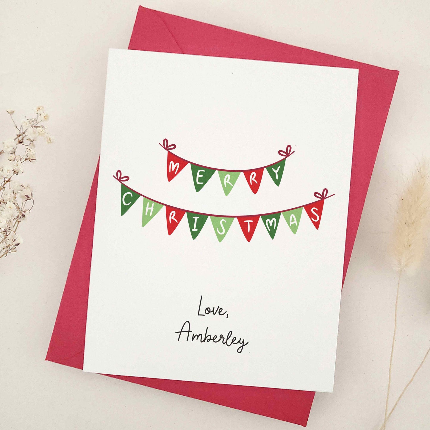 Embrace the festive season with our classic 'Merry Christmas' card: a beautifully simple yet elegant choice featuring traditional Christmas bunting in warm holiday colors, delicately spelling out heartfelt holiday greetings.