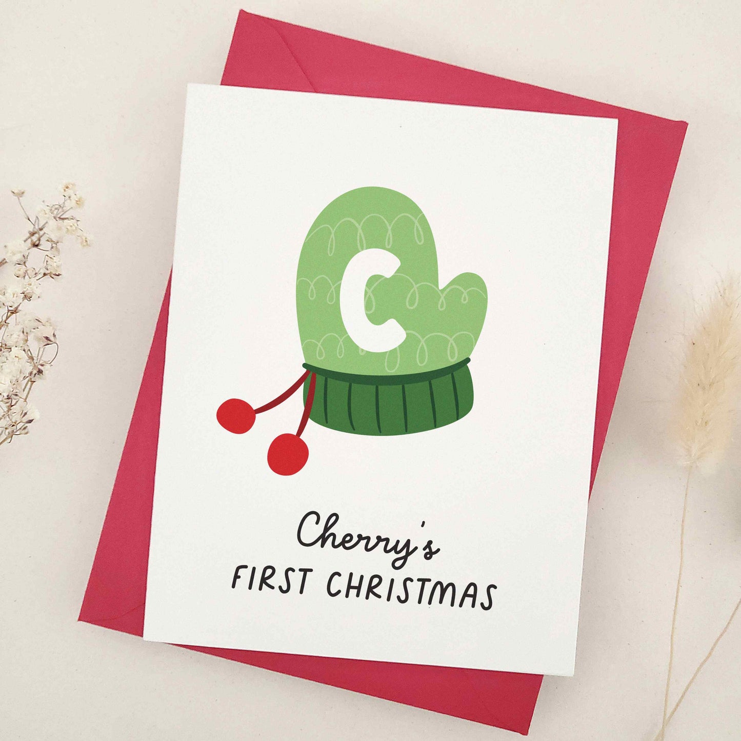 Share the happiness and joy of the season with a heartwarming design featuring a cozy green winter mitten adorned with a playful initial, perfect for marking a little one's introduction to time-honored holiday traditions. This delightful card captures the essence of a child's first experience with the magic of yuletide, making it a cherished keepsake for years to come.