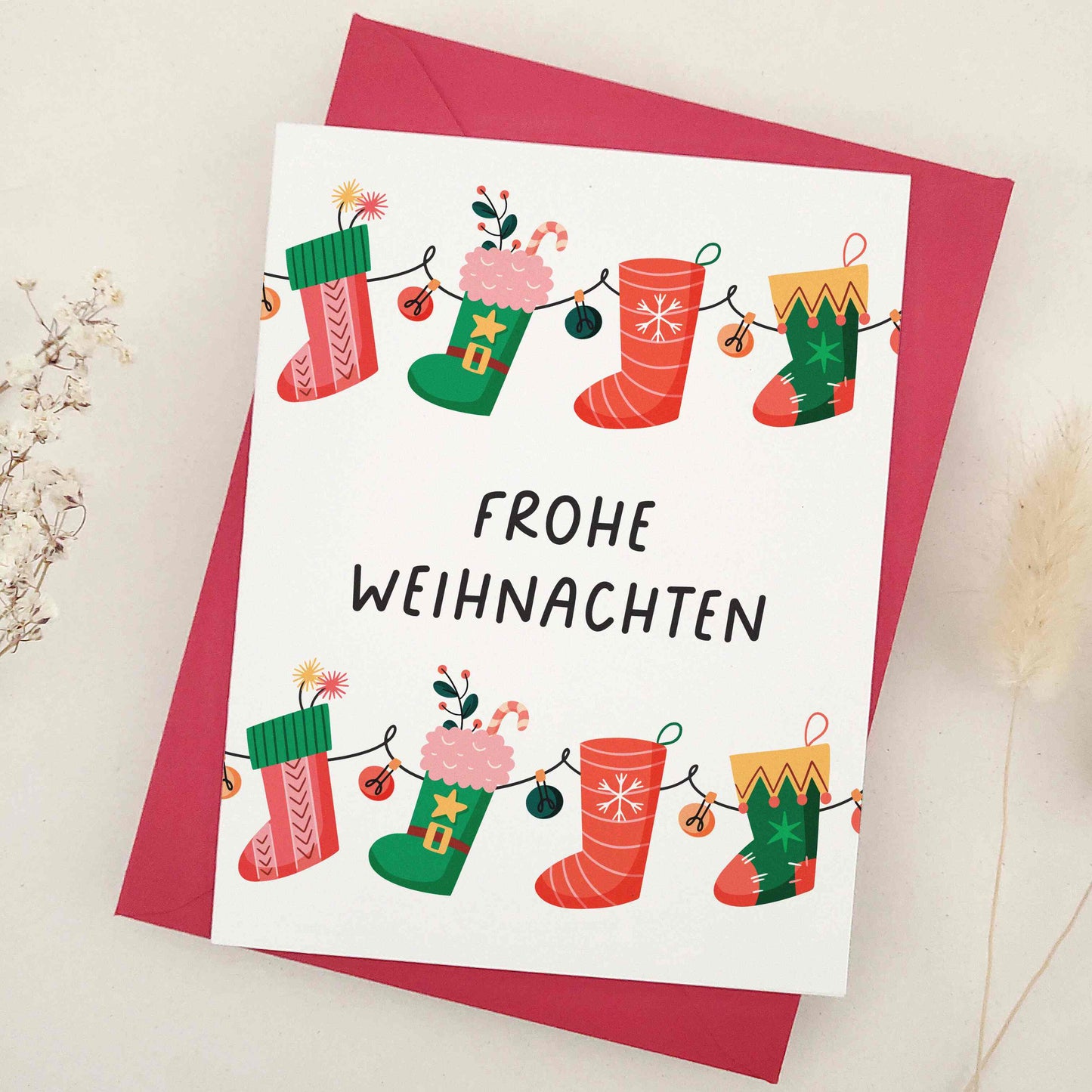Delightful 'Frohe Weihnachten' card adorned with whimsical Christmas stockings, each festively decorated to capture the cozy and cheerful spirit of the season. The stockings, strung together like a garland, symbolize the connection and joy of the holidays. This card combines traditional German holiday charm with a touch of whimsy, making it perfect for sharing festive wishes.