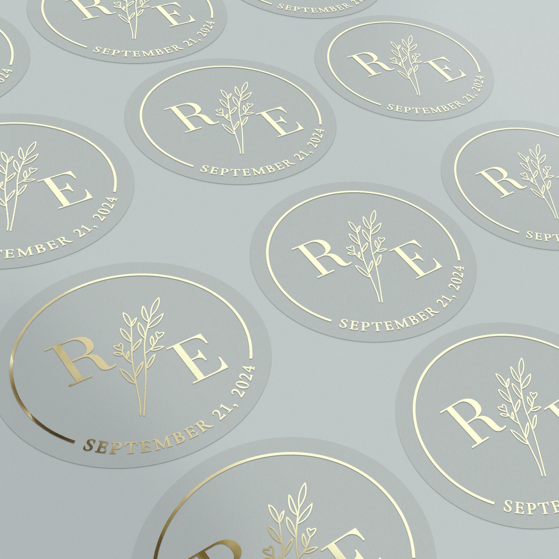 Transparent wedding sticker with golden initials and date, featuring an elegant botanical design