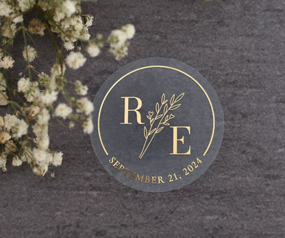 Transparent wedding sticker with golden initials and date, featuring an elegant botanical design