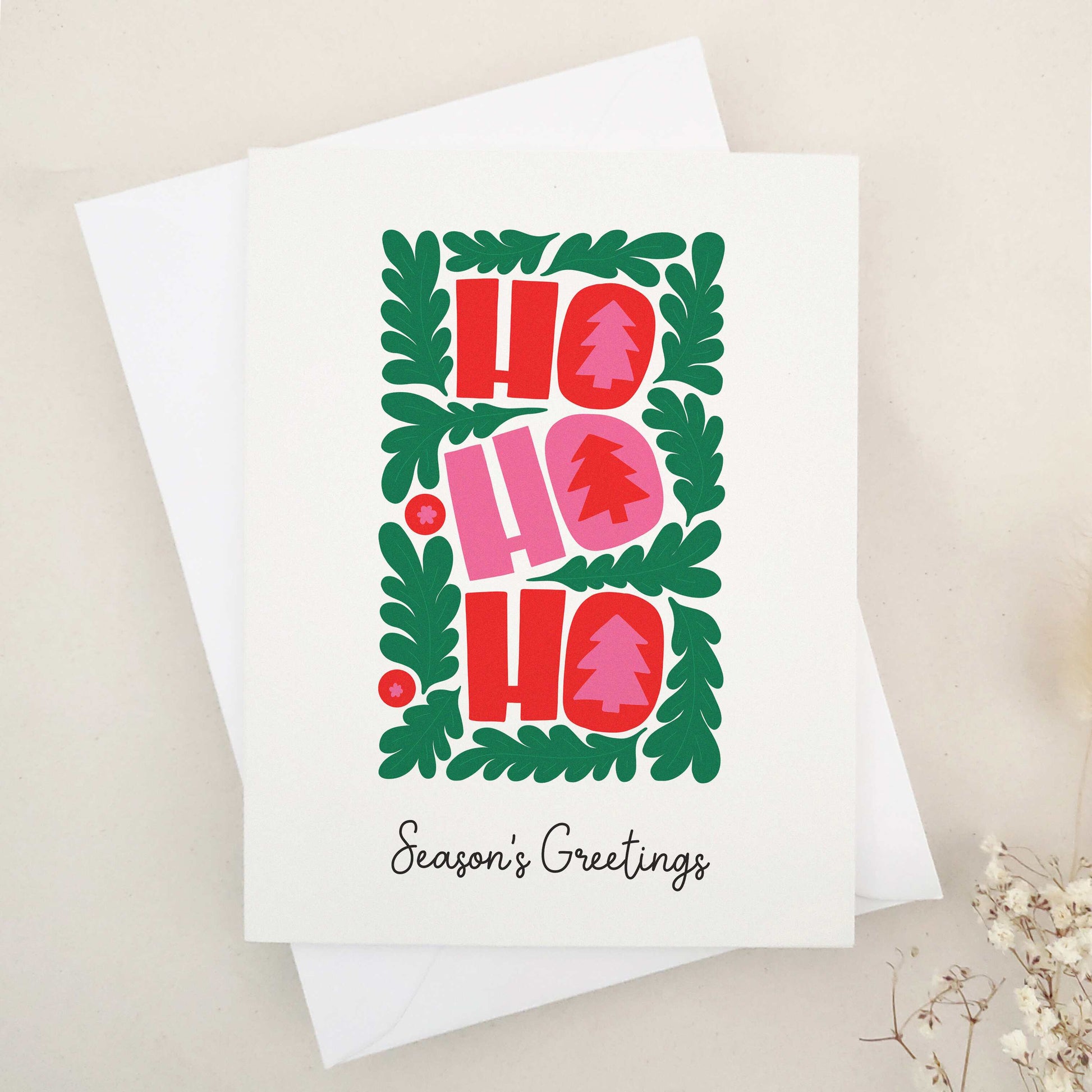 Spread holiday cheer with our vibrant 'HO HO HO' Season's Greetings card, featuring a festive wreath and bold Christmas trees, a delightful and eye-catching way to brighten the holiday season for friends and family.
