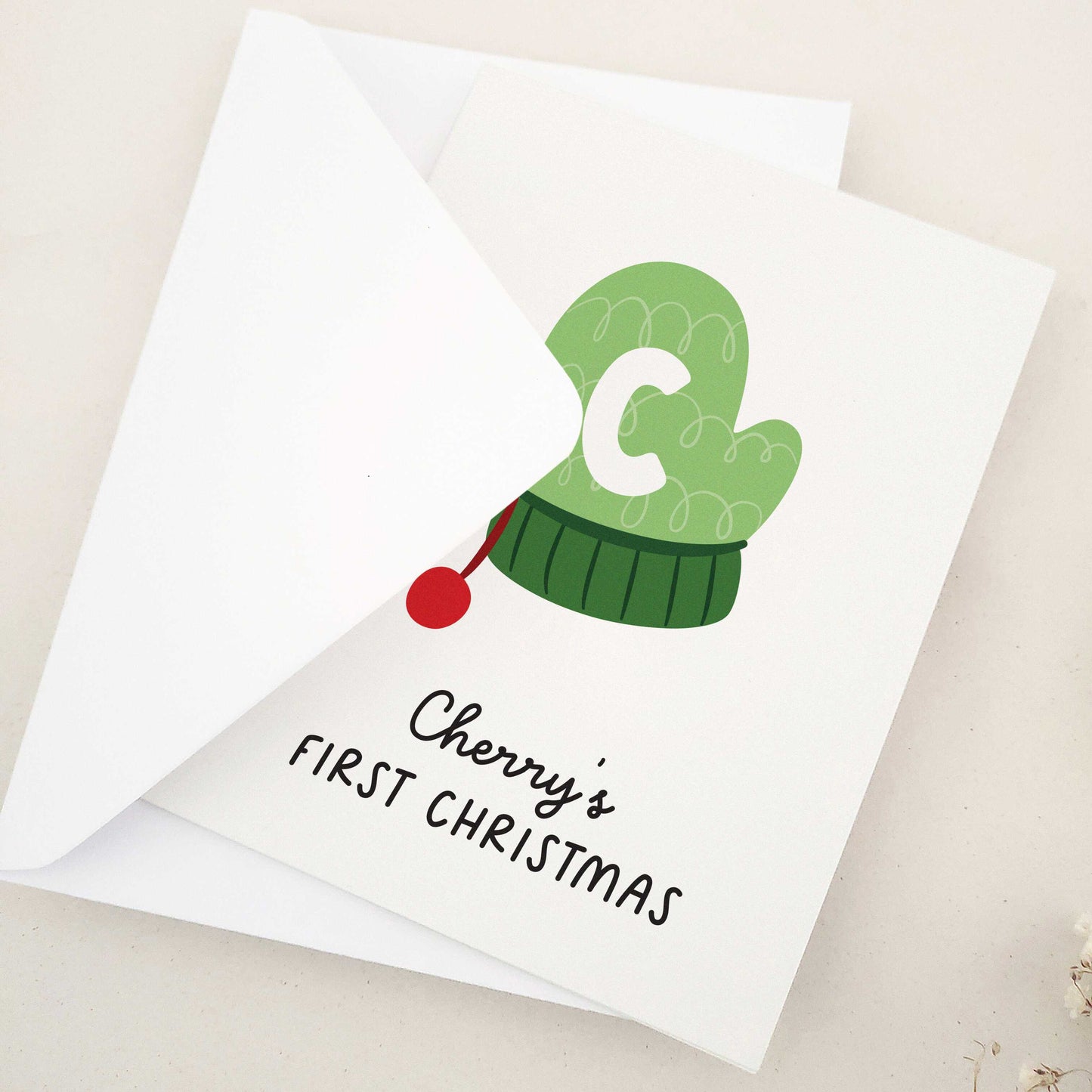 Share the happiness and joy of the season with a heartwarming design featuring a cozy green winter mitten adorned with a playful initial, perfect for marking a little one's introduction to time-honored holiday traditions. This delightful card captures the essence of a child's first experience with the magic of yuletide, making it a cherished keepsake for years to come.