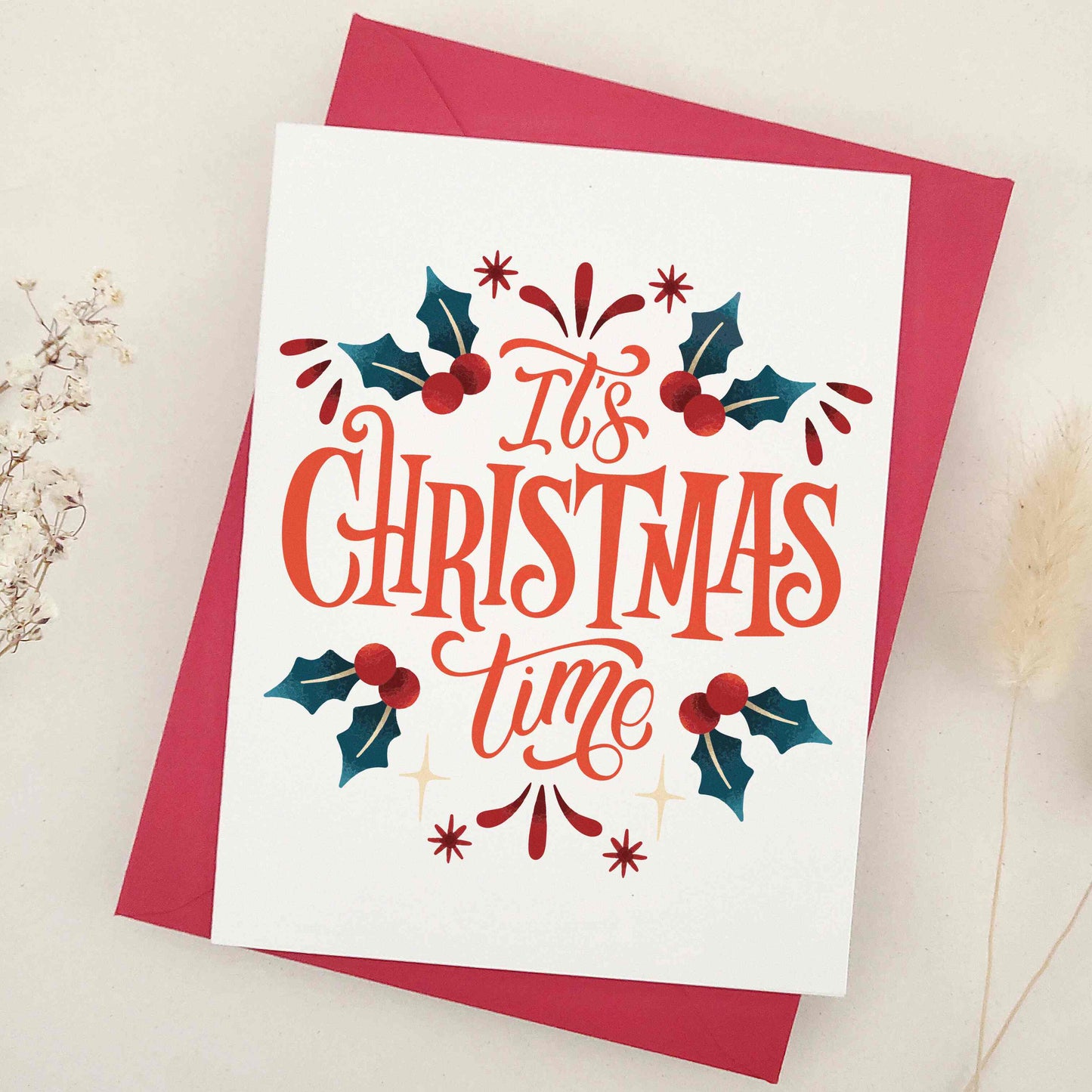 Elegant 'It's Christmas Time' card, lavishly expressing holiday excitement and joy, adorned with traditional holly leaves and berries. Features a beautifully styled typographic design as the centerpiece, joyously announcing the season and capturing the essence of holiday merriment. This card combines classic holiday imagery with modern typographic flair, making it a sophisticated and festive choice for season's greetings.