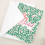 Folded holiday card featuring bold mistletoe leaf pattern with berry accents, framing the words “Feliz Navidad” in flowing calligraphy, displayed with envelope — XOXOKristen.