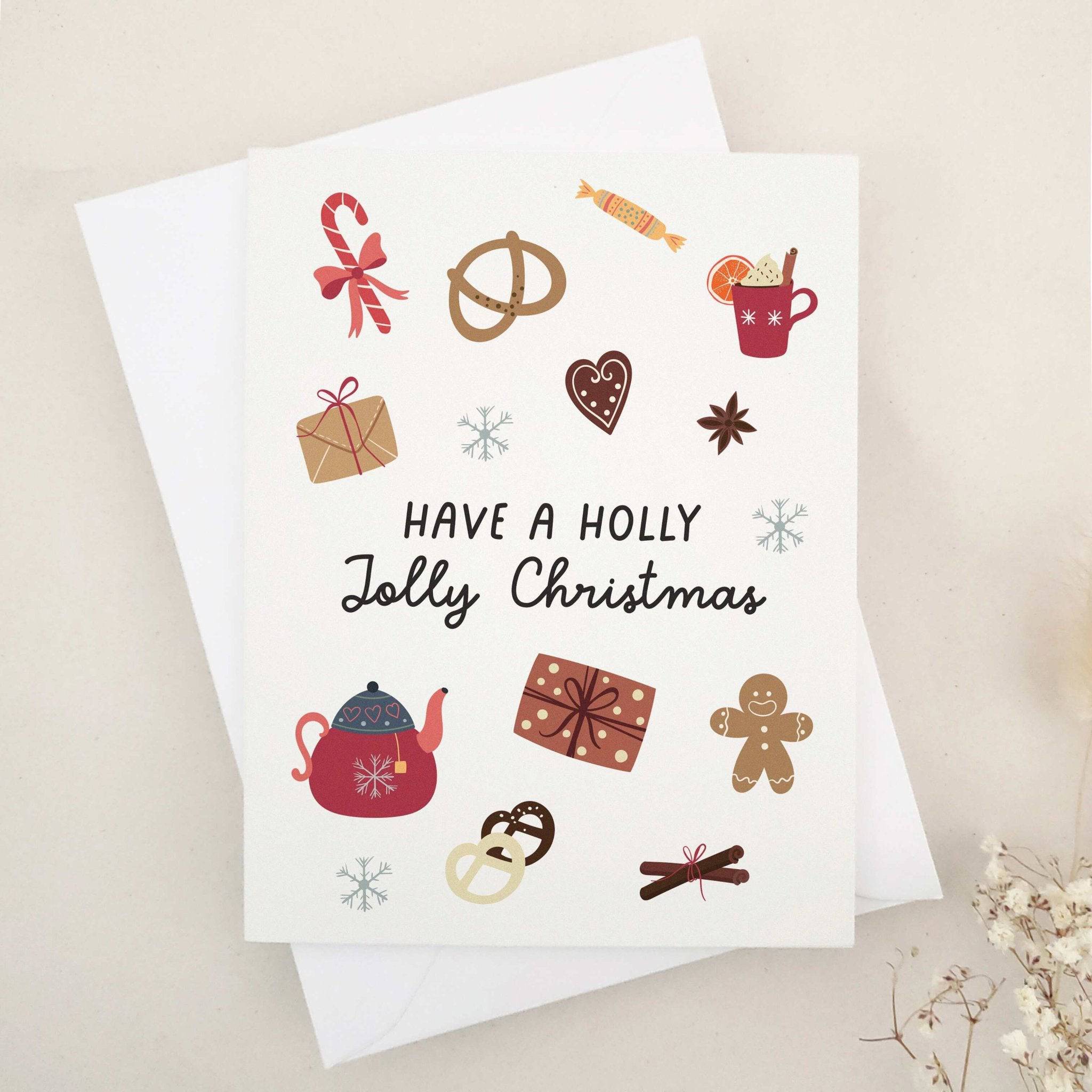 Folded holiday card featuring playful festive icons like gingerbread, candy, snowflakes, ribbon, and hot cocoa mug, displayed with envelope — XOXOKristen.