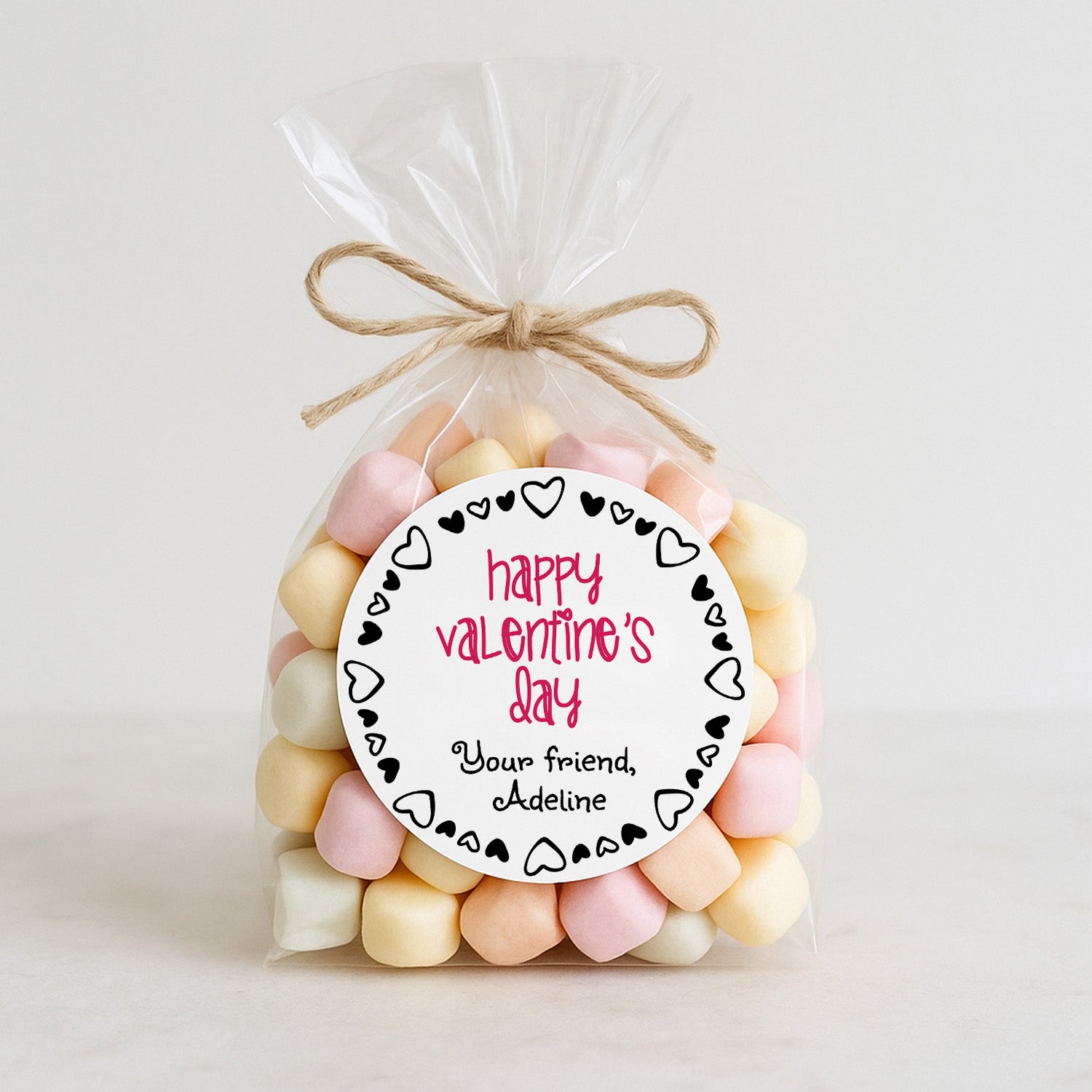 XOXOKristen personalized round Valentine’s Day sticker on a clear bag filled with pastel marshmallows, red and black heart border design – XOXOKristen
