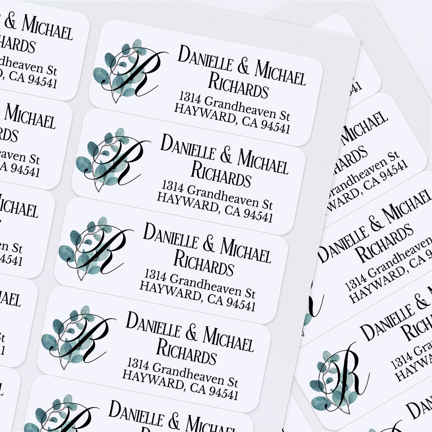 Custom address label stickers displayed on pink and burgundy envelopes, featuring monogram with green eucalyptus design and serif typography - XOXOKristen