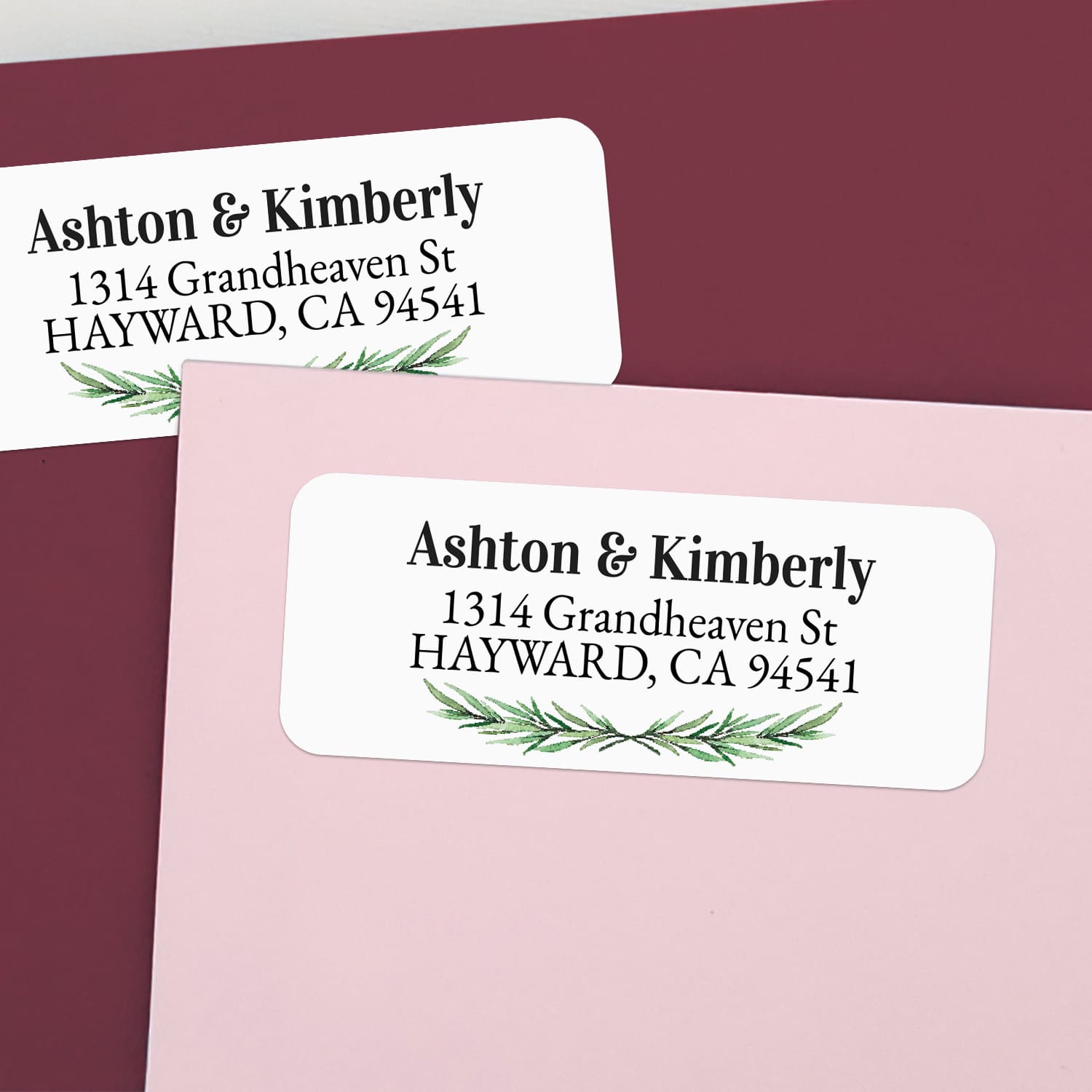 Custom return address labels on pink and burgundy envelopes, decorated with watercolor pine branch motif and classic serif text - XOXOKristen