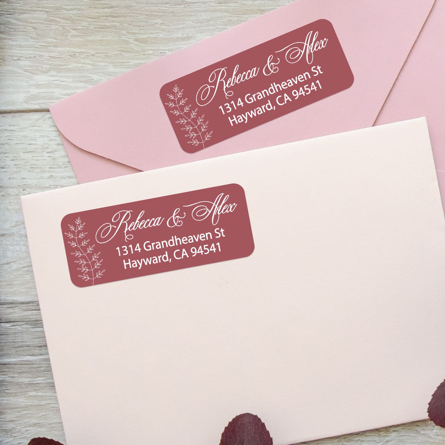 Close-up of burgundy return address sticker with graceful white calligraphy script and botanical branch motif, printed on rectangular label - XOXOKristen
