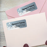 Custom holiday return address labels on pink and burgundy envelopes, featuring snowy houses, moon, and Santa sleigh design - XOXOKristen