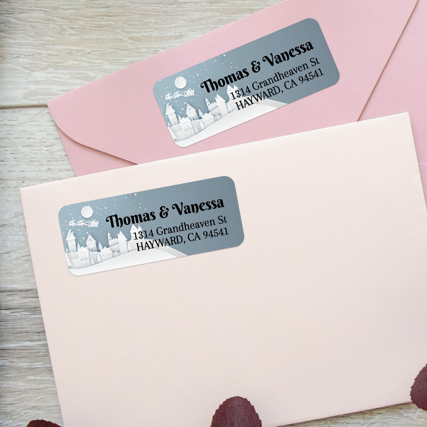 Custom holiday return address labels on pink and burgundy envelopes, featuring snowy houses, moon, and Santa sleigh design - XOXOKristen