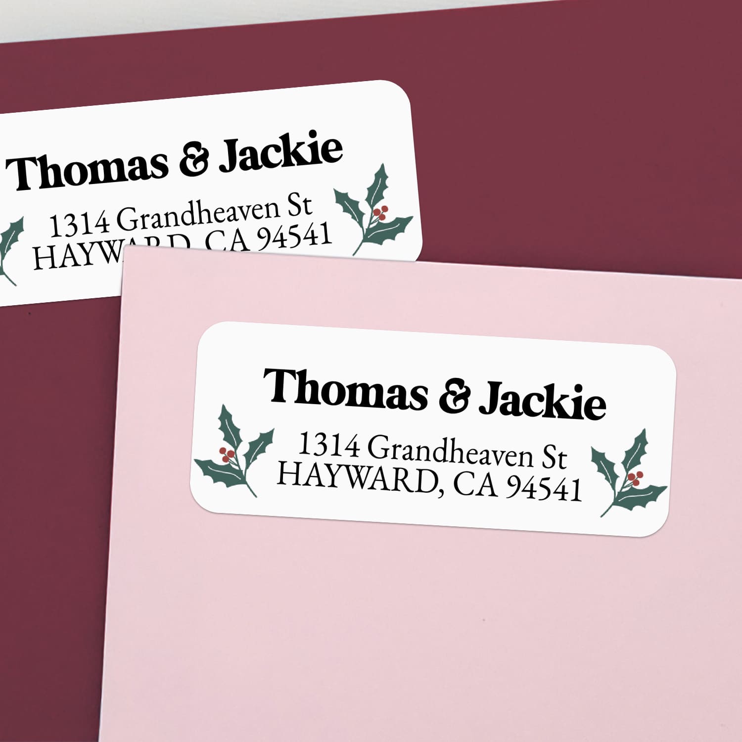 Custom Christmas return address labels on pink and burgundy envelopes, decorated with festive holly branch motifs and printed text - XOXOKristen