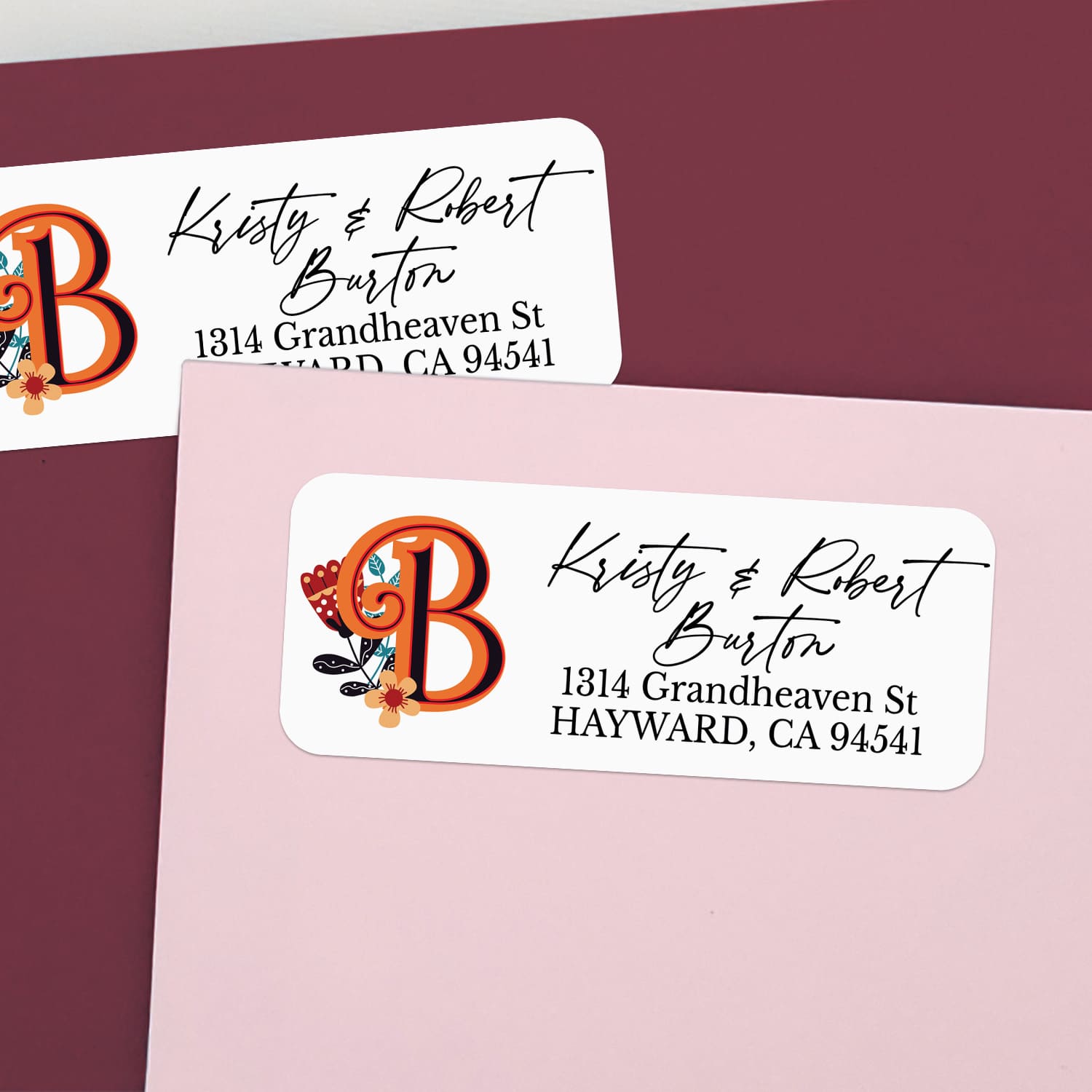Custom return address label on pink and burgundy envelopes, featuring decorative orange monogram with flower illustration and elegant calligraphy text - XOXOKristen