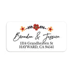 Rectangular return address label with floral border of red and yellow flowers, featuring modern black script for names and serif text for address, on white background — XOXOKristen.