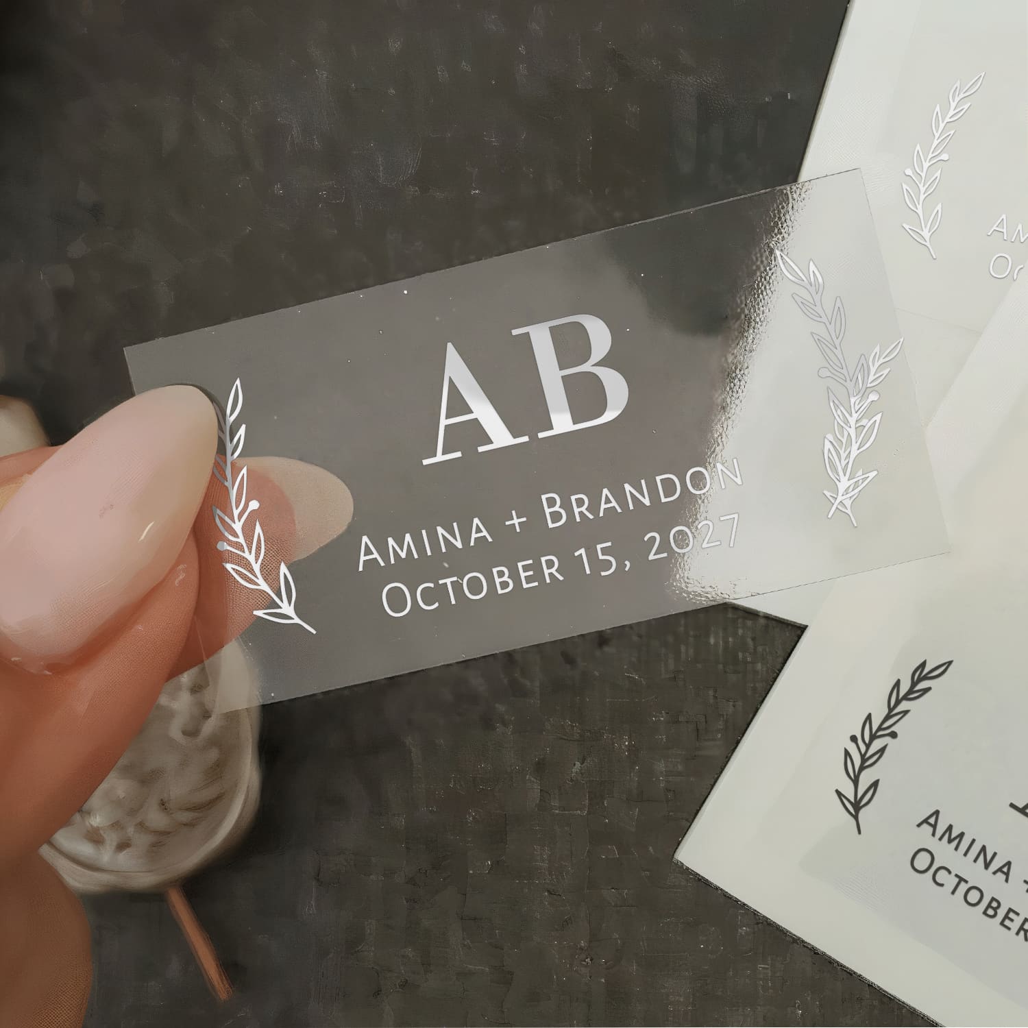 Transparent clear vinyl wedding sticker with glossy finish, featuring central serif initials framed by delicate botanical leaves – XOXOKristen.