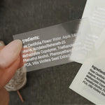 XOXOKristen custom clear ingredient label held in hand, transparent glossy finish, printed with product formulation details - XOXOKristen