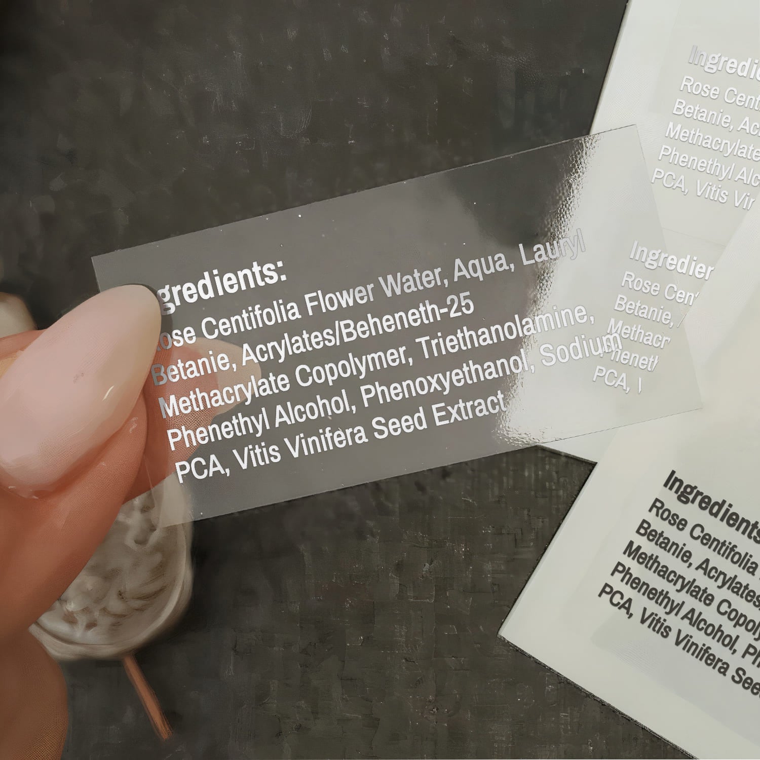 XOXOKristen custom clear ingredient label held in hand, transparent glossy finish, printed with product formulation details - XOXOKristen