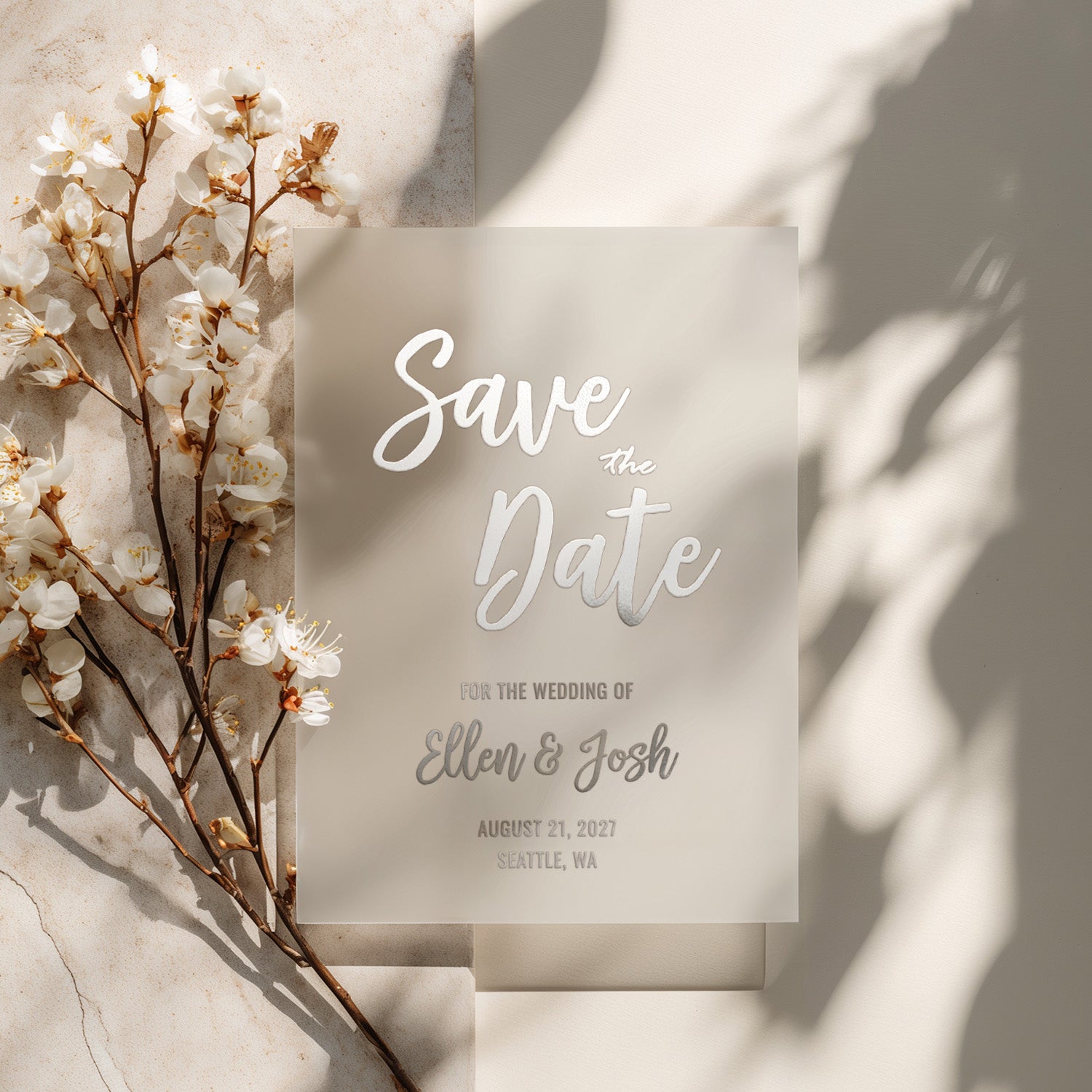 XOXOKristen custom vellum Save the Date card printed in metallic silver foil with elegant calligraphy and classic layout, surrounded by white spring flowers on soft neutral background – XOXOKristen.