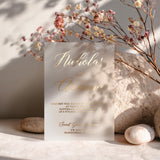 Elegant vellum invitation card with gold foil printing displayed on soft stone background with pastel flowers and subtle shadows. Perfect for modern or luxury wedding announcements. - XOXOKristen