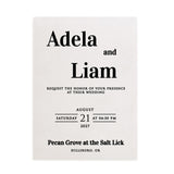 A translucent vellum wedding invitation printed in black ink with bold serif typography and minimalist design layout. The text is centered and clean, giving the invitation a timeless, contemporary look. Includes an elegant white envelope. Perfect for formal or modern weddings – XOXOKristen.
