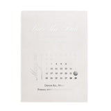 Vellum “Save the Date” wedding card with delicate white calligraphy, minimalist layout, surrounded by blooming white florals and soft sunlight – XOXOKristen