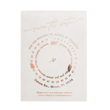 Transparent vellum Save the Date card with rose-gold foil accents and circular layout, styled on warm stone background with dried florals – XOXOKristen