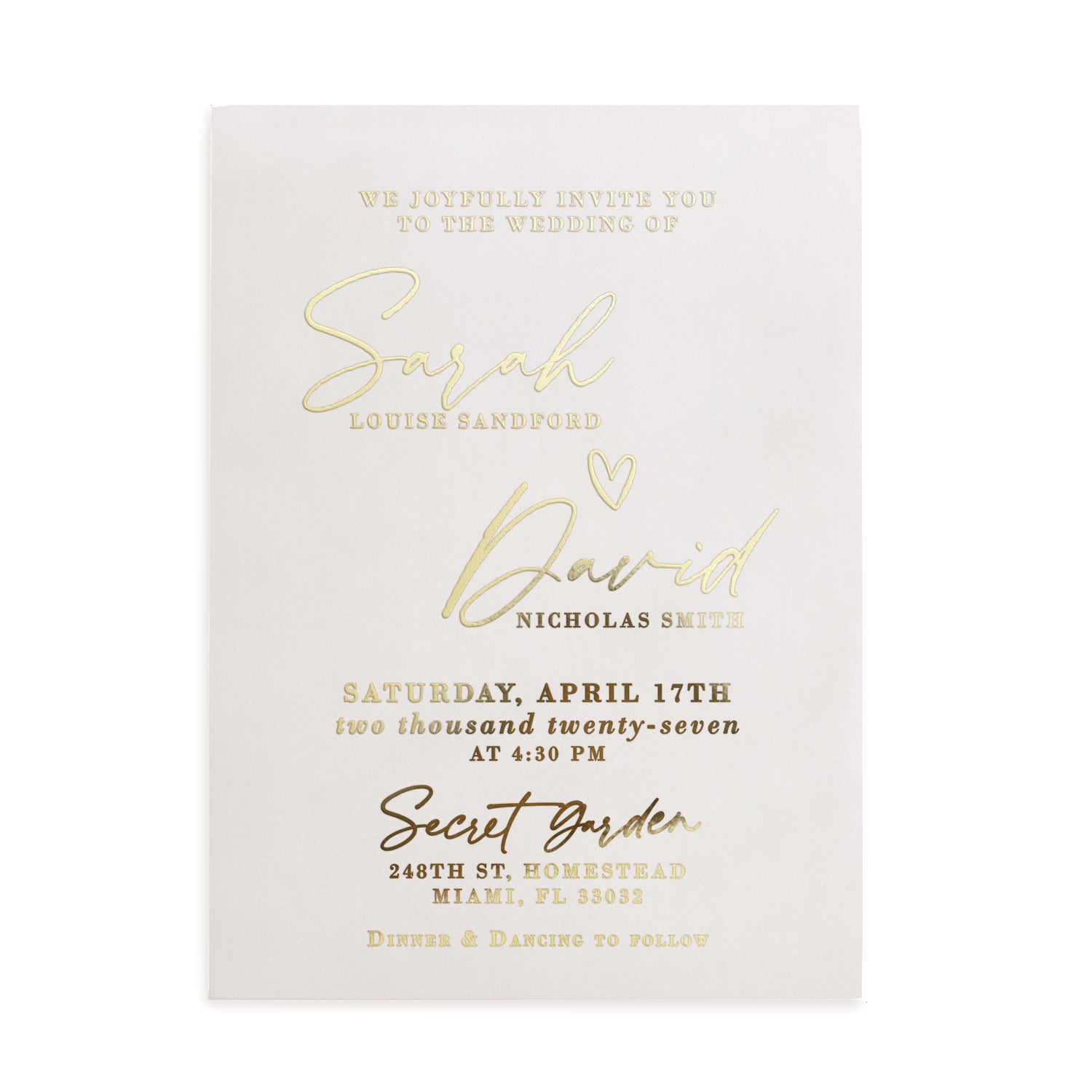 A vertical display of a translucent vellum wedding invitation featuring luminous gold foil lettering, positioned upright among natural stone and dried floral stems. The soft sunlight and gentle shadows enhance the reflective golden accents and the frosted vellum texture, creating a refined, romantic mood. The composition captures the modern luxury of personalized wedding stationery. – XOXOKristen