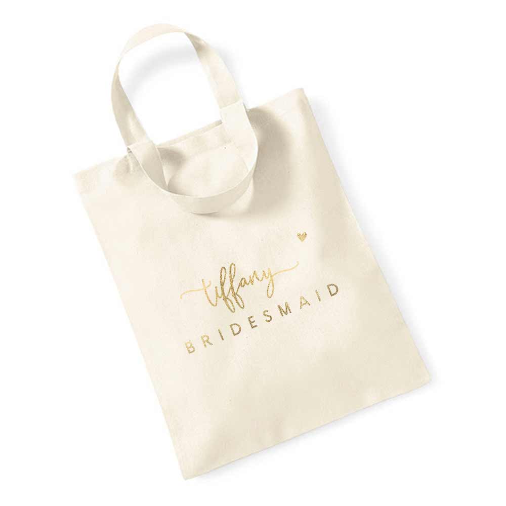 Personalized bridesmaid tote bag with gold foiled lettering and heart accents. Customizable for as maid of honor, flower girl, matron of honor or other custom wedding roles – XOXOKristen
