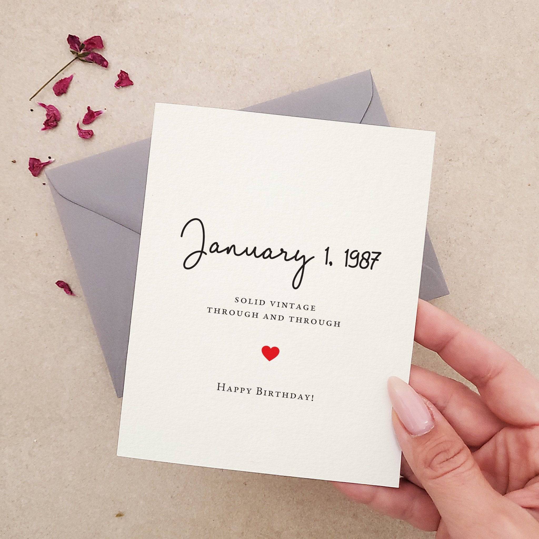 Birthday card with personalized date on the front, reading “Solid vintage through and through. Happy Birthday!” in black script and serif fonts with a small red heart, paired with gray envelope — XOXOKristen.