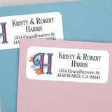 Close-up of white rectangular return address label with large blue and red monogram H, floral decoration, and black personalized address text - XOXOKristen